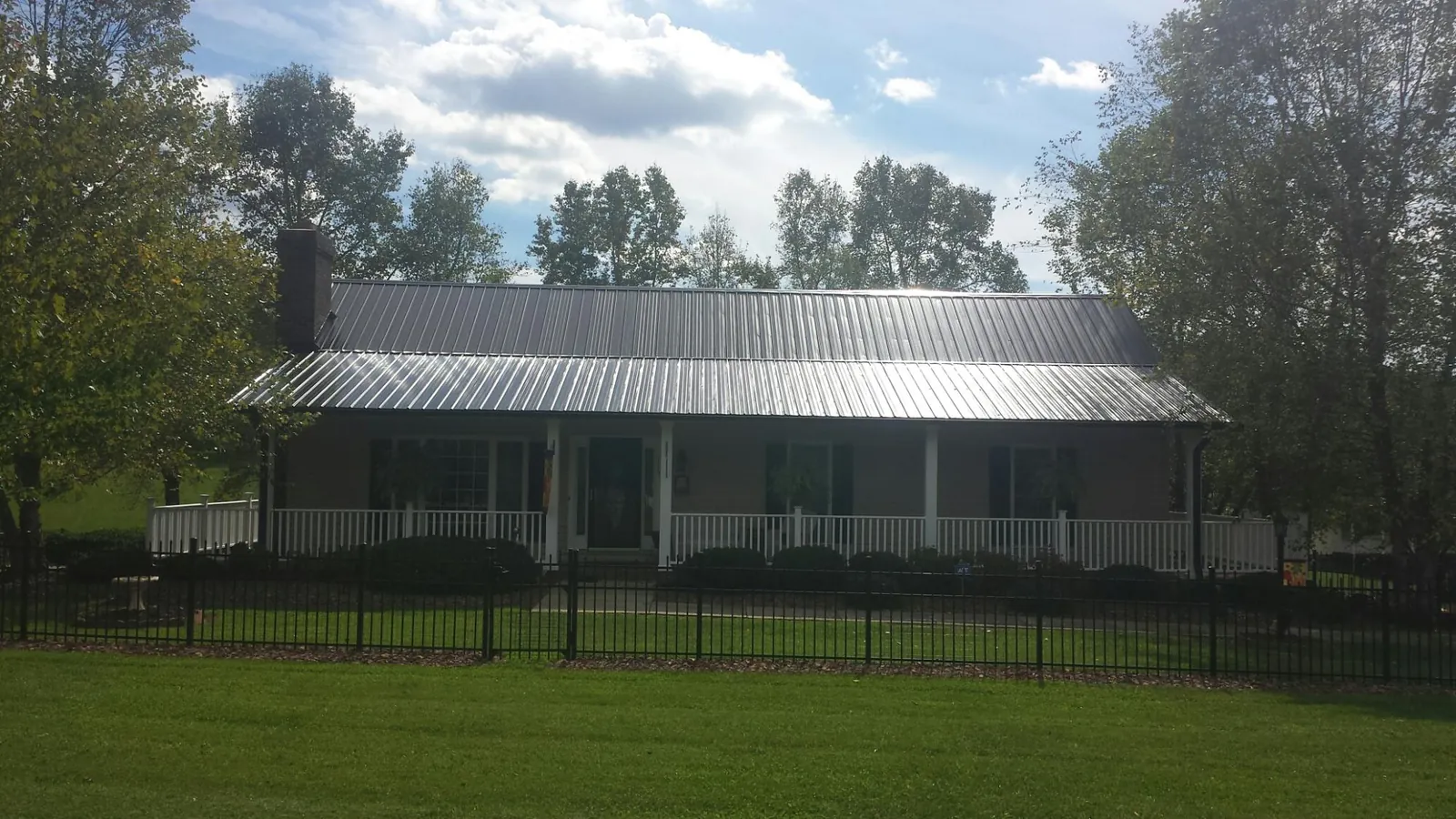 Gray metal roof on a brick ranch with a full width front porch — Gutter Guard Installation work by our crew in Prattsburgh